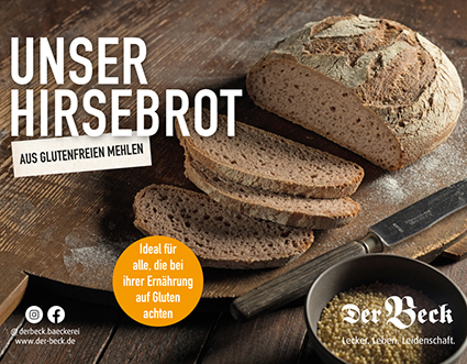 Ein aufgeschnittenes Hirsebrot auf einem Holzbrett, daneben ein Messer und eine Schale mit Hirsekörnern