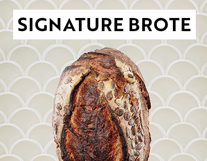 Ein Laib Kürbiskernbrot mit wilden Hefen vor einer beigen Kachelwand